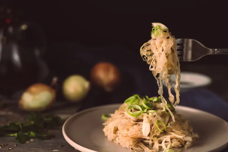A mouthwatering plate of sauerkraut garnished with green onions, ready to eat