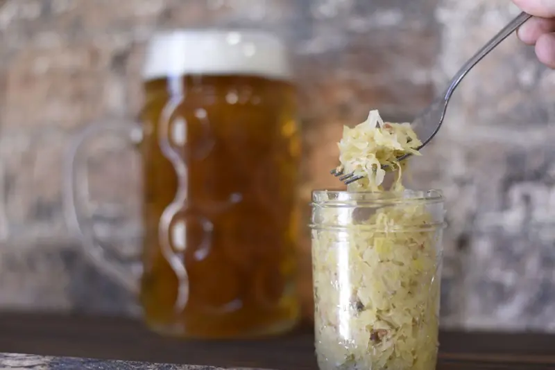 A rustic setting featuring a frothy beer mug and sauerkraut in a jar, perfect for pub themes