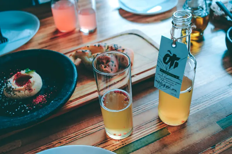 Chic indoor dining setup with a glass of kombucha and gourmet appetizer on a wooden table