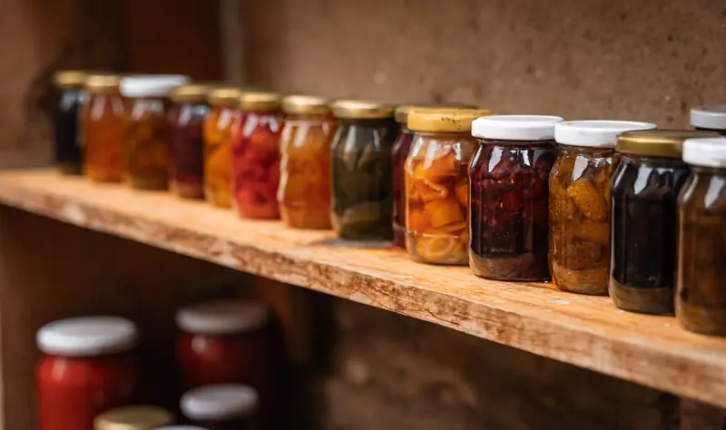 Homemade preserves in mason jars neatly arranged on a rustic wooden shelf