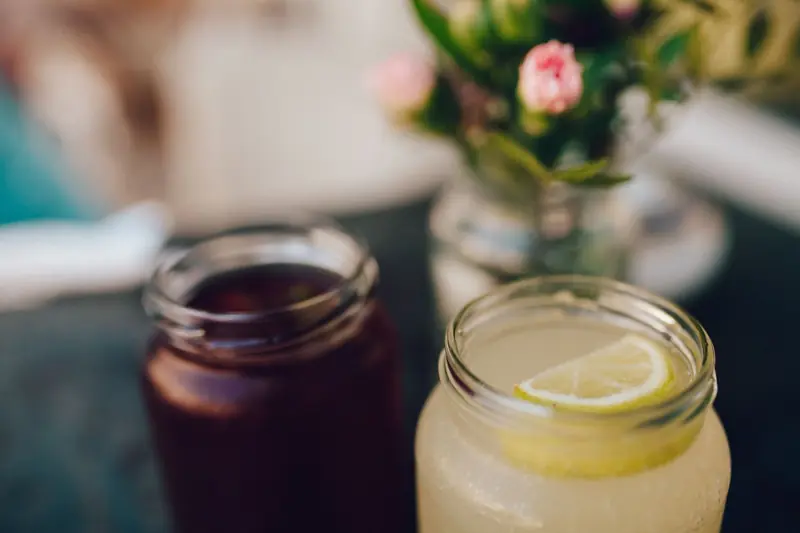 Close-up of refreshing citrus drinks in mason jars with flowers in the background