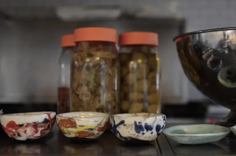 Artistic close-up of colorful ceramic bowls and jars of fermented food on a kitchen counter