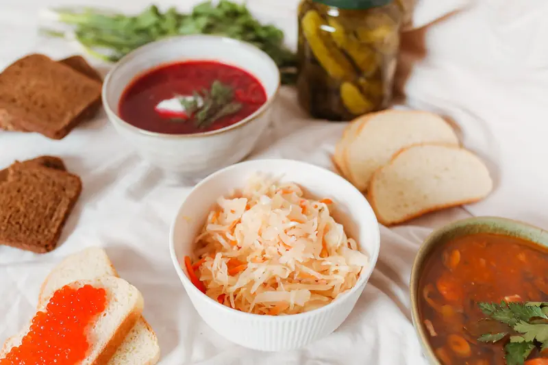 A diverse spread featuring Russian foods like borscht, sauerkraut, and caviar on a table